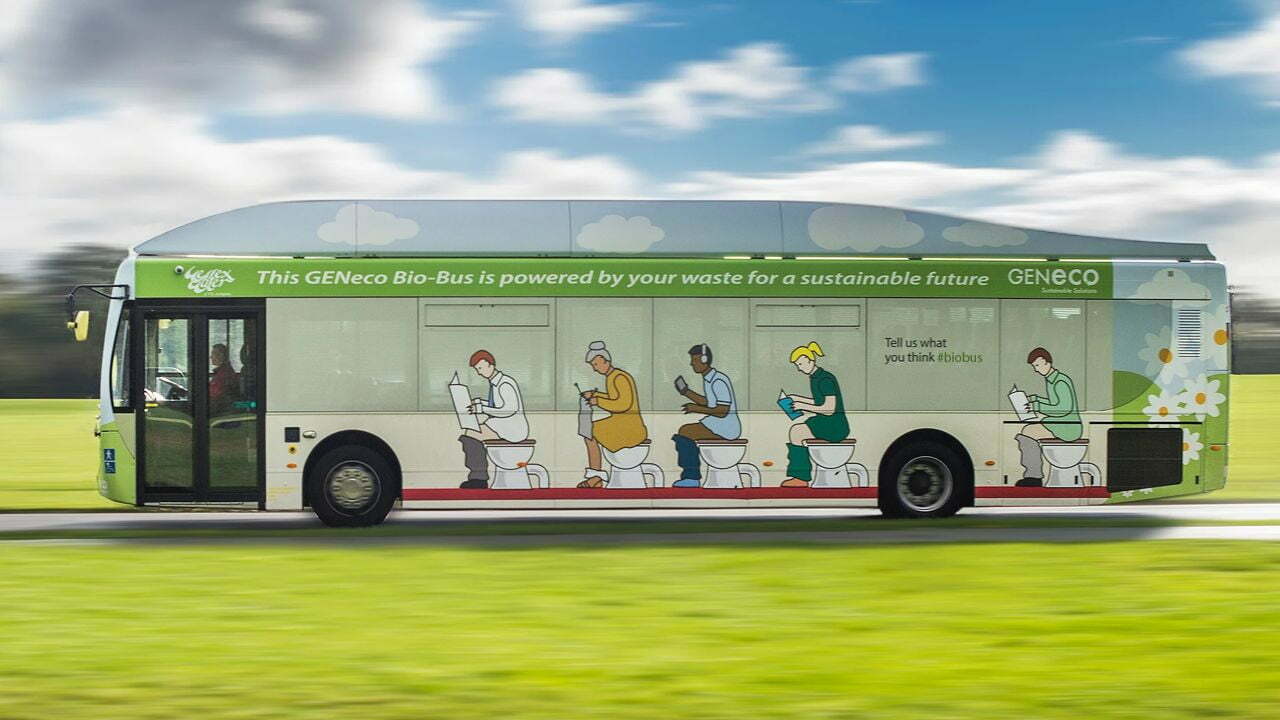 Ein Bus, der durch eine grüne Landschaft fährt. Auf der Seite sind fünf Personen, die alle auf der Toilette sitzen, abgebildet.