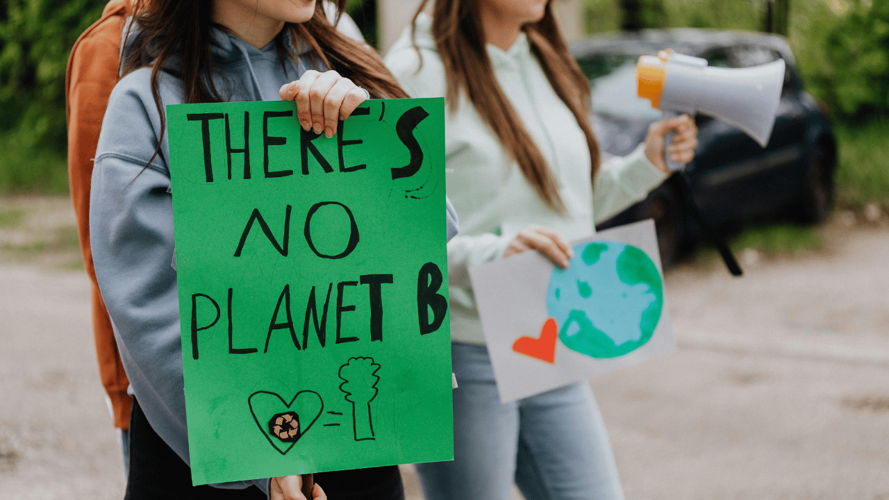Zwei Menschen halten ein grünes Schild mit der Aufschrift 'There is no Planet B' bei einer Klimademo.